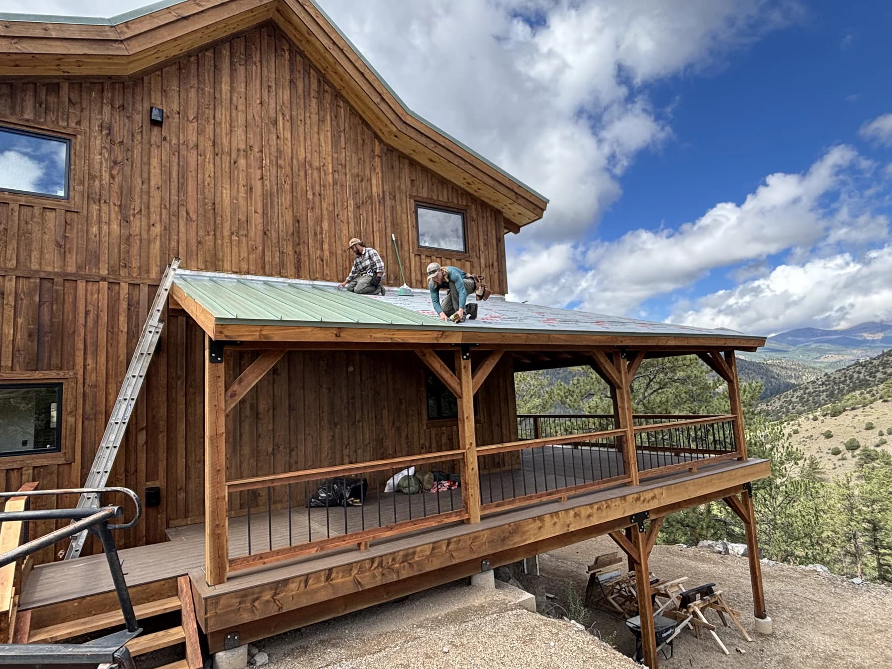 Two Ascension crew members working on the porch roof of a wood-sided house
