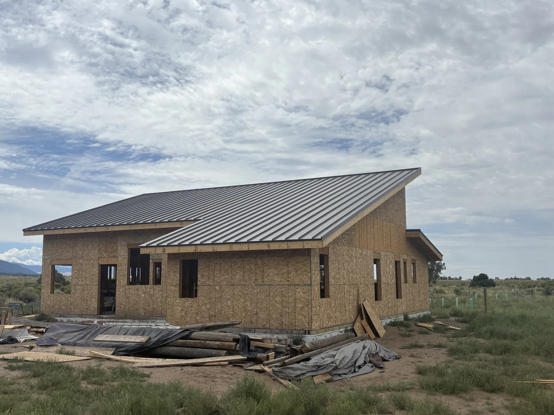 Metal roofing installed on the same new home while exterior construction continues.