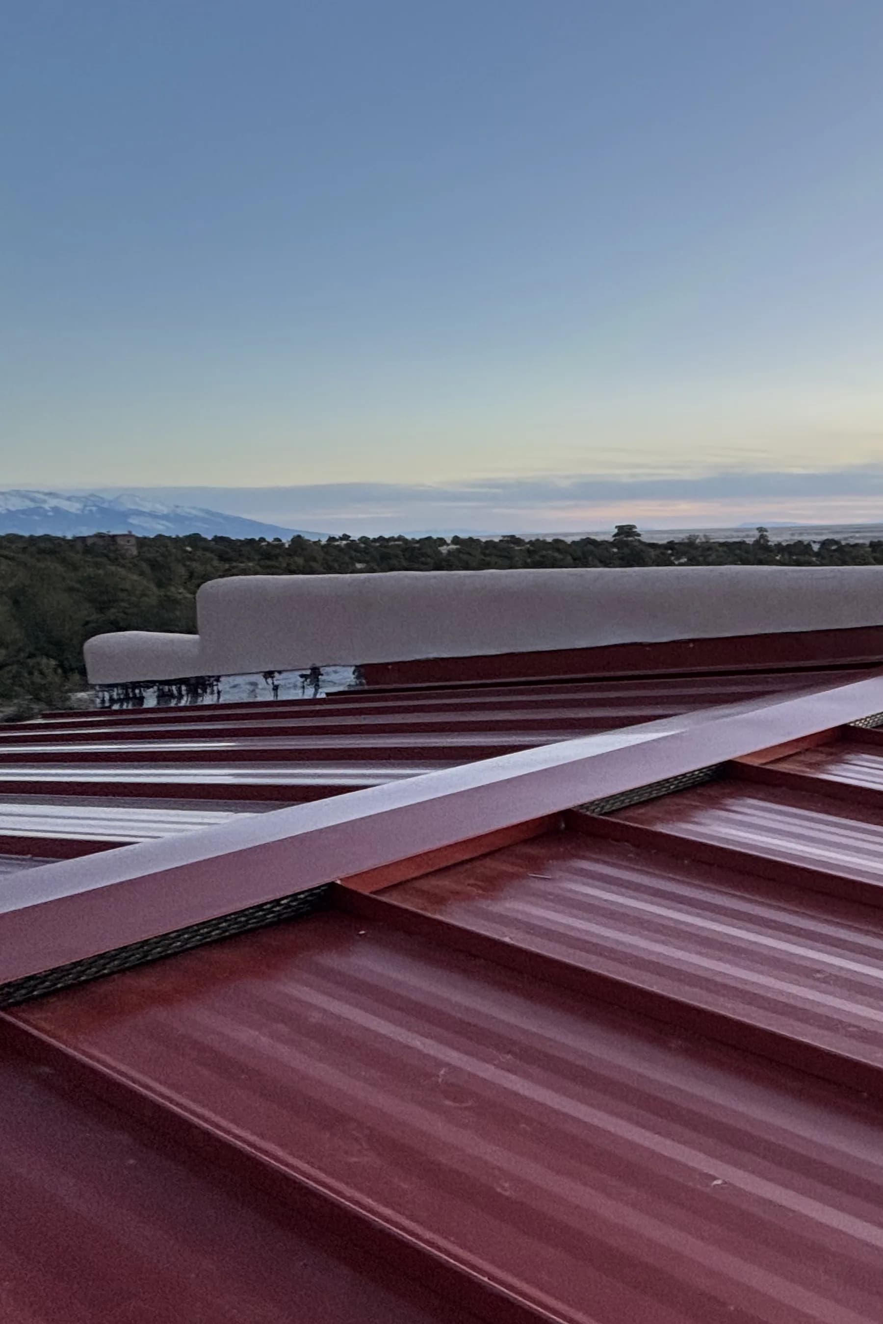 Completed barn-red standing-seam roof on a Crestone home at sunset