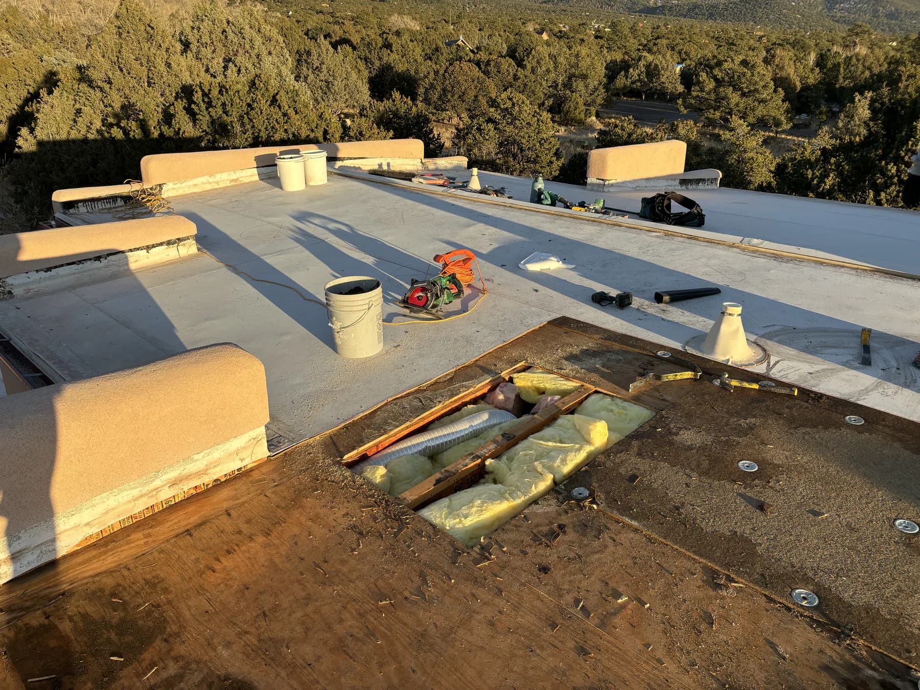 Existing TPO roof opened to expose a bathroom exhaust duct ending in a rafter bay