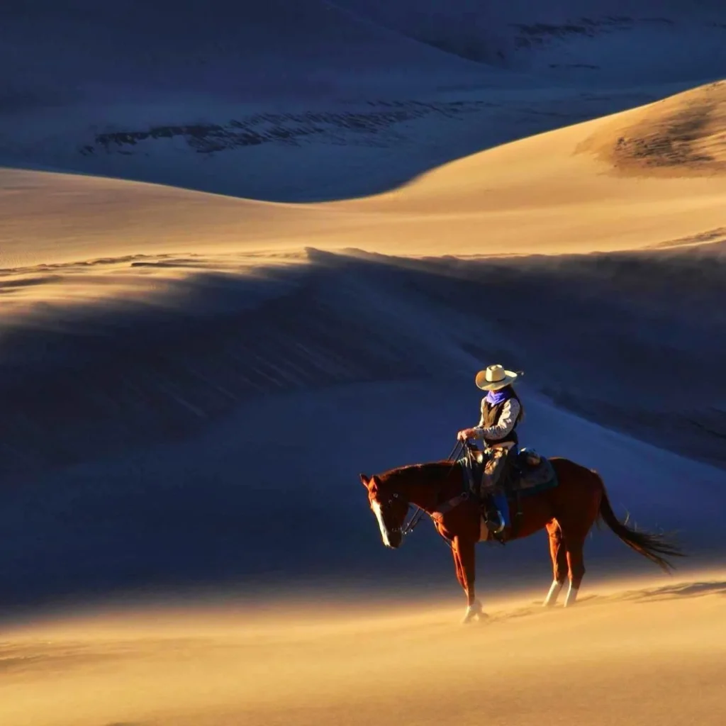 A cowgirl on a horse in the Great Sand Dunes